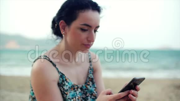 年轻快乐的高加索女人在海边使用智能手机视频的预览图