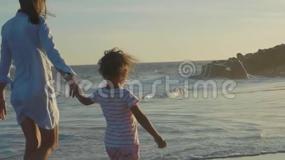 母亲带着婴儿在海边慢动作地牵着手走着视频的预览图