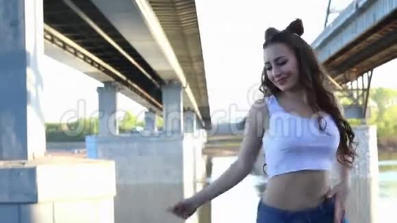 快乐美丽的女孩在桥的背景下跳舞视频的预览图