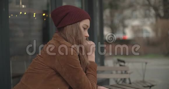 美丽悲伤的女人独自坐在户外餐馆里视频的预览图