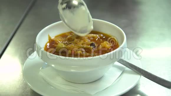 厨房餐厅厨师把汤倒在碗里以奶油和绿色装饰视频的预览图