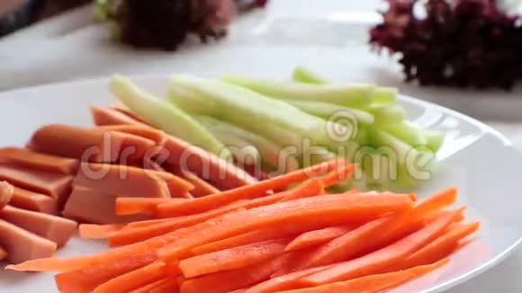 胡萝卜香肠黄瓜蔬菜在白桌上做沙拉卷视频的预览图