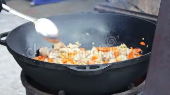 美味多汁的肉用大碗里的蔬菜炒起来在街头美食节上用勺子混合视频的预览图