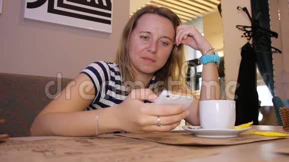 一个女人正在咖啡馆里用电话和一杯咖啡视频的预览图