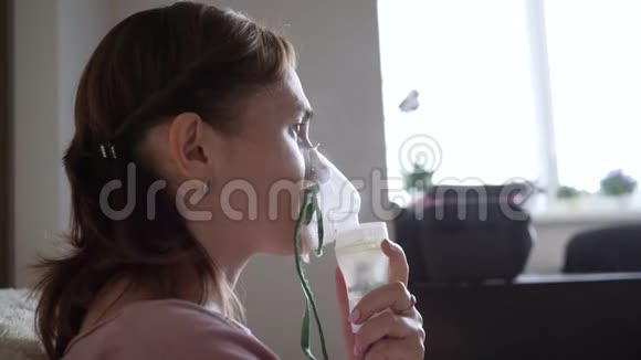 一个女人坐在家里的沙发上通过吸入器吸入面部吸入面罩视频的预览图
