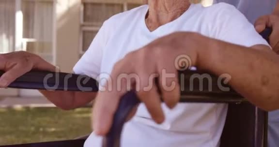 男医生在后院帮助坐轮椅的老妇人视频的预览图
