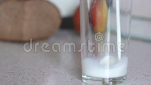 新鲜的天然牛奶倒进桌子上的玻璃杯里视频的预览图