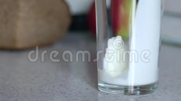 新鲜的天然牛奶倒进桌子上的玻璃杯里视频的预览图