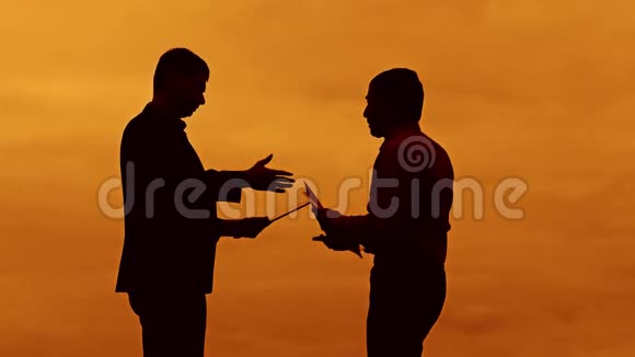 商人讨论日落剪影阳光站立剪贴板的概念两个商人握手见面视频的预览图