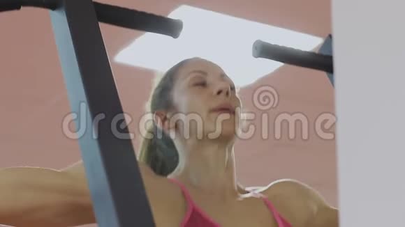 体育俱乐部的健身教练在模拟器上做拉力以加强肩部肌肉一个女人做视频的预览图