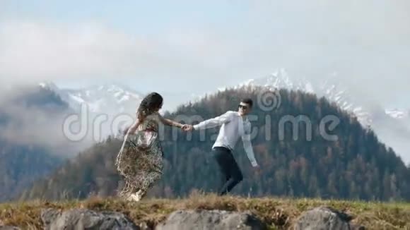 这对牵着手的夫妇正在山上的草地上奔跑视频的预览图