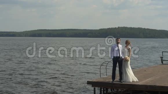 新娘和新郎站在码头上婚礼日视频的预览图
