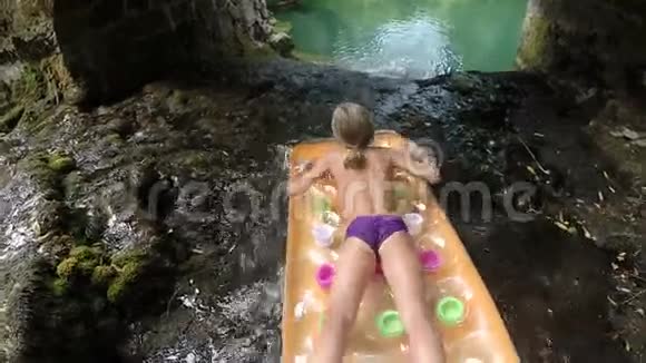 一个年轻的女孩在漂浮的床垫上走下瀑布视频的预览图