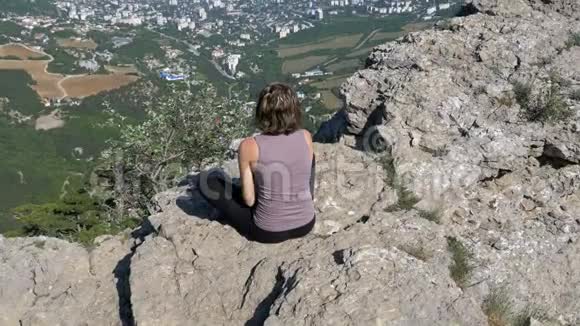 坐在莲花位置的女人练习瑜伽动作或冥想并在山上举起她的手臂视频的预览图