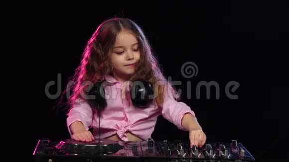 可爱的女孩在DJ控制台上玩黑色背景慢动作视频的预览图