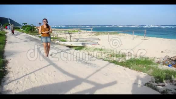 年轻的亚洲女孩在海滩上报道新闻视频的预览图