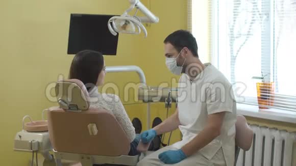 在手术前带面罩的男性牙医与女性病人交谈视频的预览图