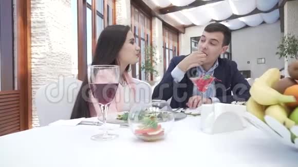 一对情侣在餐厅晚餐时一个男人在一段吻盘视频中用浆果喂一个女孩视频的预览图