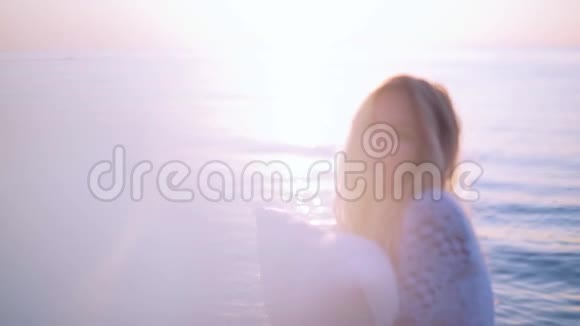沙滩上有枕头的女孩轻轻抱住她看着镜头慢动作光漏视频的预览图