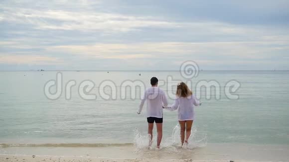 幸福的一家人牵着手沿着海岸奔跑在水里奔跑会产生飞溅视频的预览图