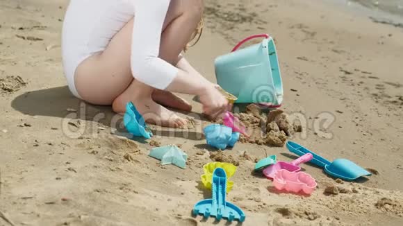 女孩在海滩上玩沙子用模子雕像夏日阳光明媚假期视频的预览图