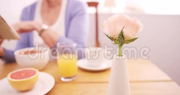 在早餐时使用数码平板电脑的老年妇女视频的预览图