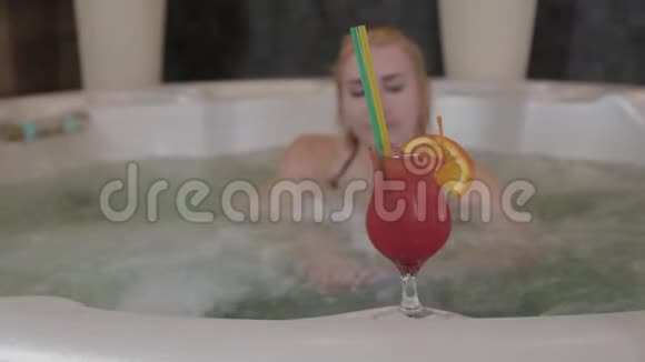 在按摩浴缸里喝鸡尾酒的漂亮女孩视频的预览图