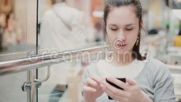 一位身穿灰色毛衣使用智能手机的黑发年轻女子视频的预览图