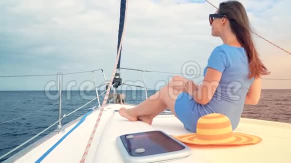 穿着黄色帽子和蓝色裙子的女人在海洋的夏季在游艇上休息慢动作视频的预览图