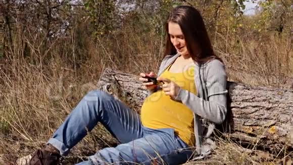 孕妇在公园里使用智能手机视频的预览图