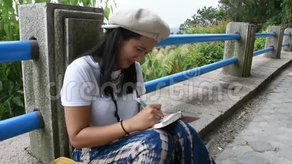 泰国妇女坐在书上写纸条以纪念旅途中的细节视频的预览图