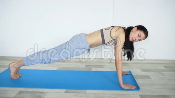 在室内垫子上做瑜伽运动的年轻女子视频的预览图