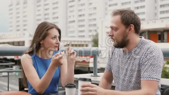 一对漂亮的年轻夫妇在街上的一家咖啡馆里一个女人在情感上告诉了男人一些事情4K视频的预览图
