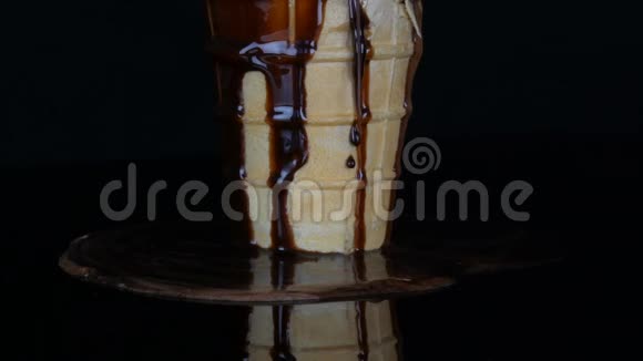 将巧克力糖浆酱汁倒入黑色背景的冰淇淋融化视频的预览图