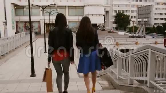快乐的年轻女性朋友带着购物袋走在桥上交谈讨论后景斯泰迪卡姆射击4K视频的预览图