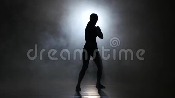 女踢脚手手套发出的拳剪影黑色背景后面的灯视频的预览图