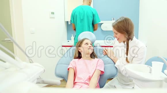 微笑牙医与年轻女性患者男性外科医生交谈背景视频的预览图