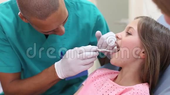 当牙医助理检查她的牙齿时要闭上女孩的嘴视频的预览图