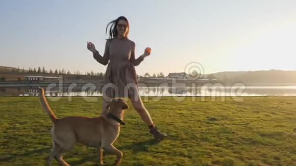 可爱的年轻女人和她可爱的狗在湖边的大自然中玩耍视频的预览图