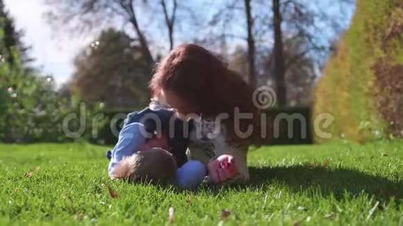 幸福的家庭在草坪上休息母亲用温柔和爱拥抱她的孩子儿子笑了快乐的童年视频的预览图