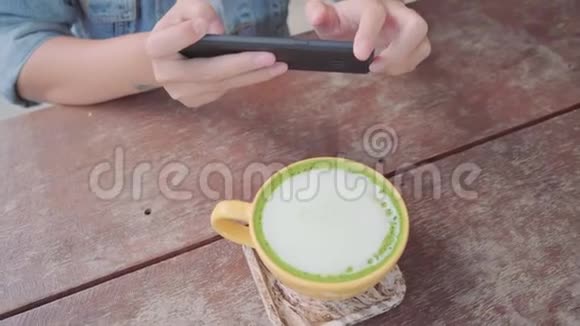 女博主用手机在咖啡馆里拍摄绿茶视频的预览图