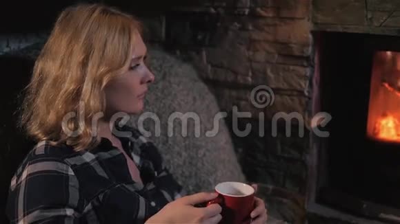年轻美丽的女人享受冬天的热饮在家的壁炉旁放松近距离拍摄视频的预览图