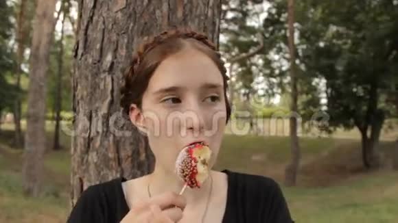 嬉皮士女孩吃糖果苹果侧视视频的预览图