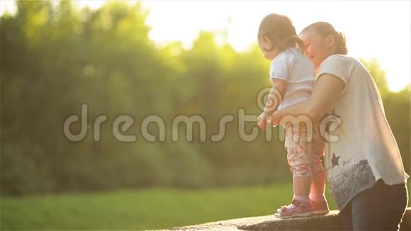 家庭花时间在大自然中母亲温柔地拥抱女儿美丽的妈妈在公园里和她的孩子玩耍视频的预览图