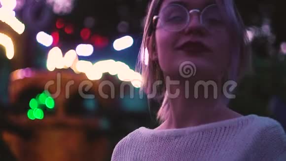 一个戴眼镜的漂亮女孩在附近的游乐园里摆姿势视频的预览图