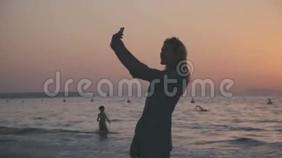 女人站在沙滩上打电话拍照视频的预览图
