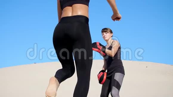 两个穿着黑色健身服的年轻女子在荒无人烟的情况下穿着一双运动服锻炼踢腿训练打架视频的预览图