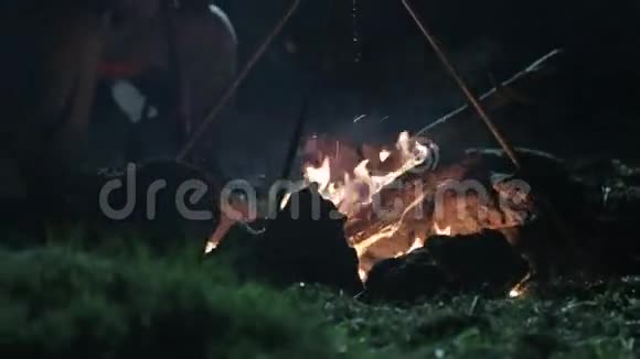 白种人坐在篝火旁边晚上用智能手机说话视频的预览图
