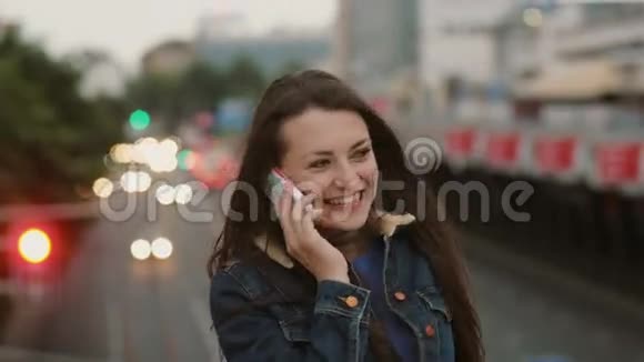 幸福的微笑的漂亮女人站在桥上打电话风吹着她的头发4K视频的预览图