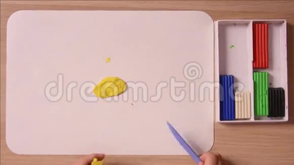 孩子把一堆黄色的塑料片剪下来用于工艺品特写俯视视频的预览图
